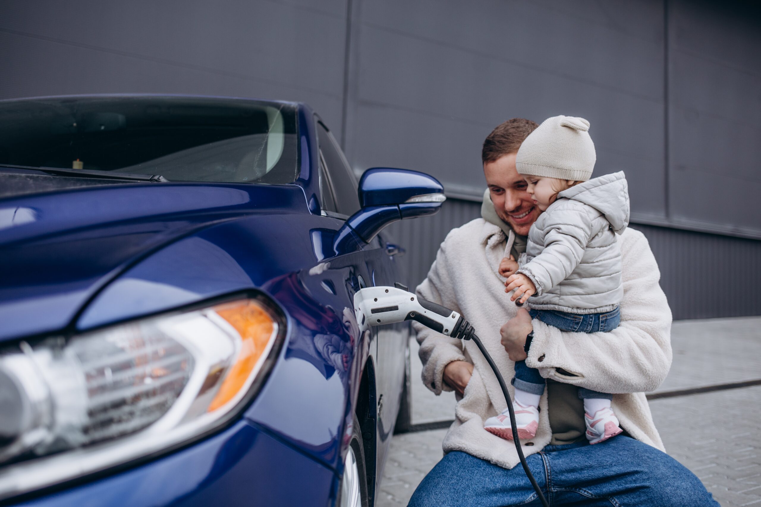 Man and child charging an electric vehicle.